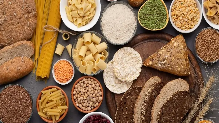 Assorted gluten-free foods including rice, pasta, lentils, bread, beans, and whole grains displayed on a table for a healthy gluten-free diet.